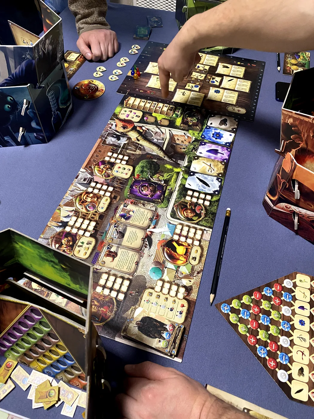 Top-down view of an Alchemists game: the board and players' hands over the tokens